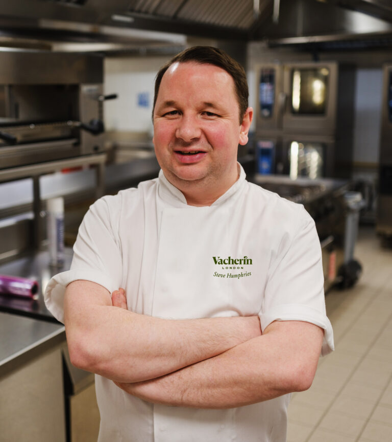 man in chef shirt smiling and crossing his arms